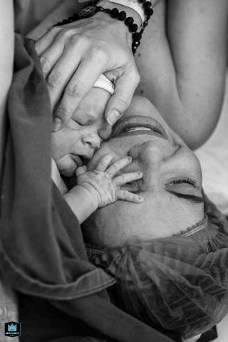 Professional photographer captures a tender moment between mother and newborn in a hospital delivery, in this tight black and white detail shot taken in Campos dos Goytacazes, Rio de Janeiro.